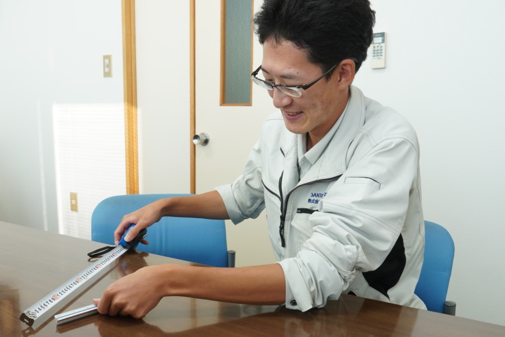 寸法を測る三角スケールの使い方を教えてくれる内藤さん